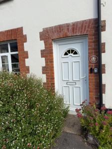 une porte blanche sur une maison en briques avec des fleurs dans l'établissement 3 Bed East Devon close to Otter Valley National Nature Reserve and sea, à East Budleigh