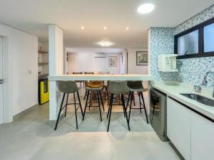 a kitchen with a bar with stools in it at Refúgio Aconchegante - Enxoval Completo Riviera in Riviera de São Lourenço