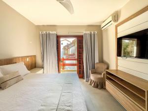 a bedroom with a bed and a tv and a chair at Refúgio Aconchegante - Enxoval Completo Riviera in Riviera de São Lourenço +62 photos