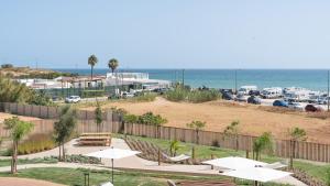 a park with tables and umbrellas and the ocean at Luxury Flats with Pool in Quarteira by LovelyStay in Quarteira