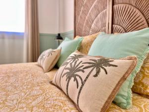 a bed with a pillow with palm trees on it at Loving Los Abrigos in Los Abrigos