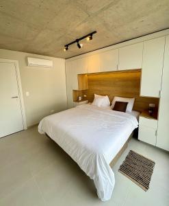 1 dormitorio con 1 cama blanca grande y cabecero de madera en First Del Sol 506 - Vivelite, en Asunción