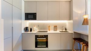 a kitchen with white cabinets and a stove top oven at Luxury Flats with Pool in Quarteira by LovelyStay in Quarteira