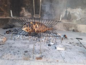 un pollo está siendo cocinado en una parrilla en Smiljin Dvor, en Nečujam