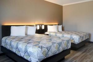 two beds with white pillows in a hotel room at Motel Worth, TX in Fort Worth