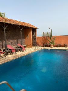 a swimming pool with red chairs and a house at Terrasse Maisonnette Chambre jardin in Rufisque