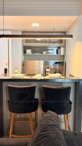 Una cocina con dos sillas negras y un mostrador. en Tropical Executive Flat Suites 507 view, en Manaus