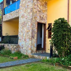 a stone house with a tree in front of it at Apartamento no Andar Inferior na Praia da Vila em Imbituba in Imbituba