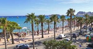 a busy beach with palm trees and the ocean at Blue Beach La Ciotat in La Ciotat