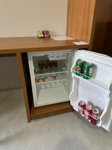 an open refrigerator with drinks in it next to a desk at Hotel Castelo do Lago in Fama