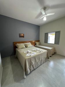 a bedroom with two beds and a ceiling fan at Castelo do Lago Hotel e Restaurante in Fama
