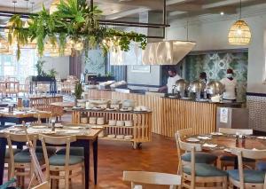 a restaurant with wooden tables and chairs and a kitchen at Blue Marlin All-Inclusive Seascape by Dream Resorts in Scottburgh