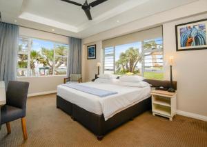 a bedroom with a bed and a chair and windows at Blue Marlin All-Inclusive Seascape by Dream Resorts in Scottburgh +23 photos