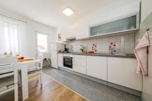 eine große Küche mit weißen Schränken und einem Tisch in der Unterkunft Ani in Trogir * Mittel-Dalmatien in Trogir