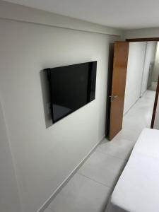 a bedroom with a flat screen tv on a wall at Edifício Flavan- Conforto e Estadia com Preços Acessíveis in Campos dos Goytacazes