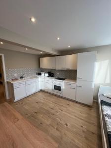 - une grande cuisine avec des placards blancs et du parquet dans l'établissement Miami Monteur Apartment, à Rodenbach