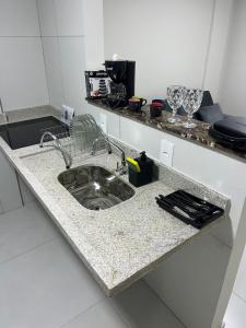 a kitchen counter with a sink and glasses on it at Edifício Flavan- Conforto e Estadia com Preços Acessíveis in Campos dos Goytacazes +23 photos