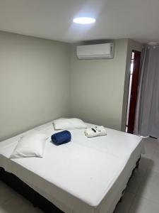 a white bed with a blue bag on top of it at Edifício Flavan- Conforto e Estadia com Preços Acessíveis in Campos dos Goytacazes