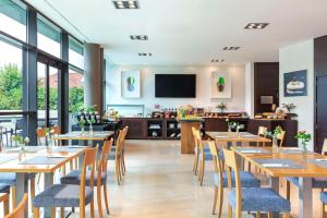 ein Restaurant mit Holztischen und -stühlen und einem Flachbildfernseher in der Unterkunft NH Gijón in Gijón