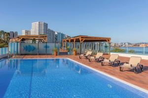 ein Swimmingpool mit Stühlen und einem Pavillon in der Unterkunft NH Gijón in Gijón