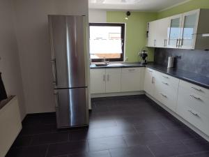 a kitchen with a stainless steel refrigerator and white cabinets at Rheinuferhaus in Urmitz