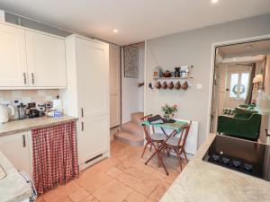 eine Küche mit einem kleinen Tisch und eine Küche mit weißen Schränken in der Unterkunft Gosling Cottage in Kendal