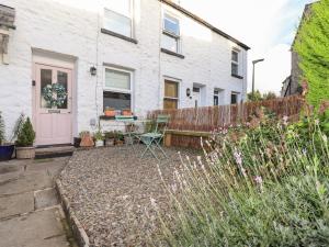ein weißes Haus mit einer rosa Tür und einem Garten in der Unterkunft Gosling Cottage in Kendal