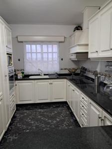 Una cocina blanca con gabinetes blancos y una ventana. en Casa Sequeira, en Fajã da Ovelha