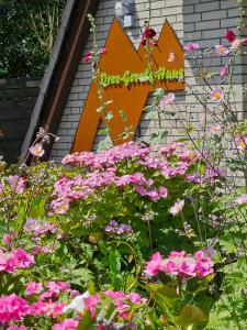 a sign in a garden with pink flowers at Ferienwohnung KUMM RIN - Oase an der Nordsee in Carolinensiel +13 photos