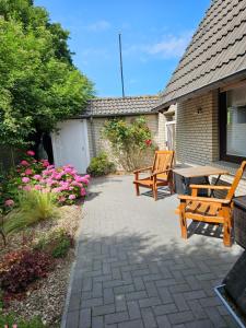 un patio con due panchine di legno e fiori di Ferienwohnung KUMM RIN - Oase an der Nordsee a Carolinensiel