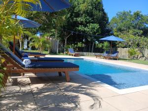 a pool with lounge chairs and umbrellas next to it at Pousada Lua Cheia Praia do Espelho in Praia do Espelho