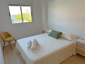 a white bedroom with a bed with towels on it at Sol y Mediterráneo in Oropesa del Mar