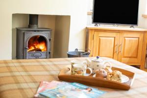 a table with a tray of food and a fireplace at Pear Tree Cottage in Blakeney