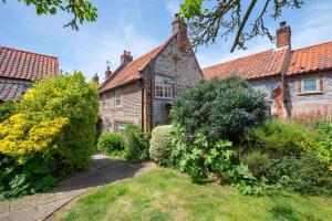 an old brick house with a garden in front of it at Pear Tree Cottage in Blakeney