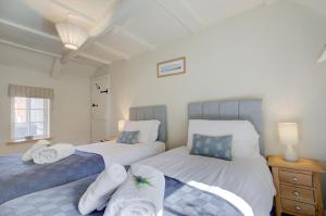 a bedroom with two beds with towels on them at Pear Tree Cottage in Blakeney