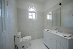 a white bathroom with a toilet and a sink at Summer Shades Villa at Legacy in Montego Bay +18 photos
