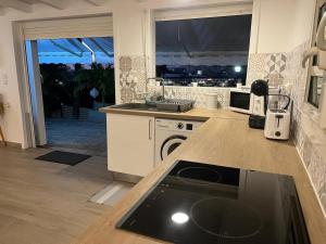 a kitchen with a counter with a sink and a stove at Logement cosy avec piscine proche de l'aéroport in Ducos