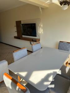 a white table and chairs in a room with a tv at Cobertura Duplex Prainha 304 in Arraial do Cabo +12 photos