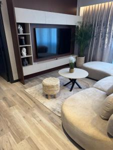 un salon avec une télévision, un canapé et une table dans l'établissement Theemeraldsuiteapartament, à Tirana