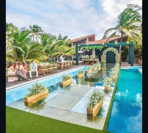 a resort with a swimming pool and people sitting around a table at Villa Ava Kite - Guajiru in Trairi