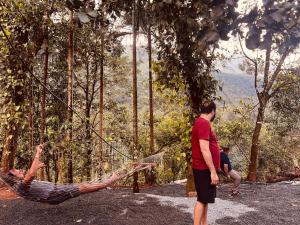 a man laying in a hammock in a forest at Bambus Alley in Wayanad