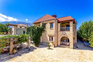a large stone house with a patio in a yard at Villa Avra by Villa Plus in Asprouliánoi