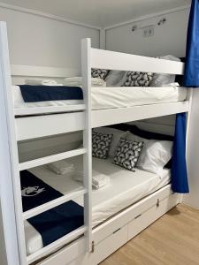 a bunk bed room with white bunk beds at Partenope Hostel and Suites in Angra do Heroísmo