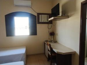 a small room with a desk and a bed and a window at Hotel São Francisco in Itaí