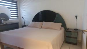 a bedroom with a white bed with a green headboard at Casa Vallarta in Cedro