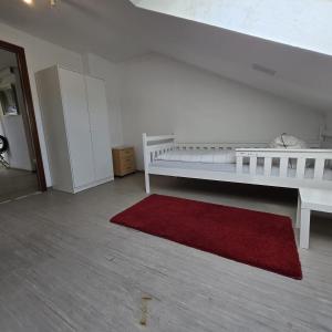 ein Schlafzimmer mit einem weißen Bett und einem roten Teppich in der Unterkunft Helles Privatzimmer mit Gemeinschaftsküche und-bad in Hannover + 1 Foto