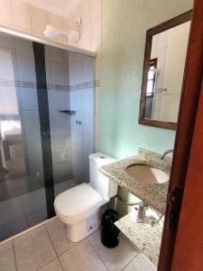 a bathroom with a toilet and a sink and a shower at Casa para Temporada na Morada da Praia em Bertioga SP in Bertioga