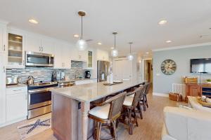 a kitchen with a large island with bar chairs at Water's Edge 105 South in Holmes Beach