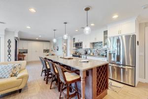 a kitchen with a large island with bar chairs at Water's Edge 105 South in Holmes Beach