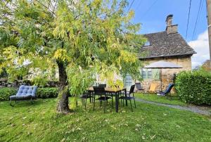 a table and chairs under a tree in a yard at Gîte de France à Darazac 2 épis - Gîte de France 2 personnes MAE-5181 in Darazac